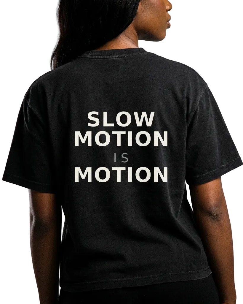 Black t-shirt with 'SLOW MOTION IS MOTION' text on the back, worn by a person.